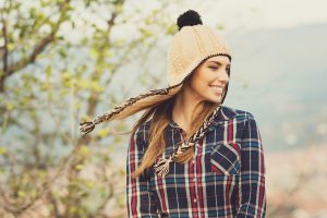 Young woman in plaid shirt and knitted hat in autumn